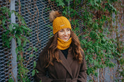 Sabbot Headwear Woman wearing matching Emma mustard knitted bobble hat and snood