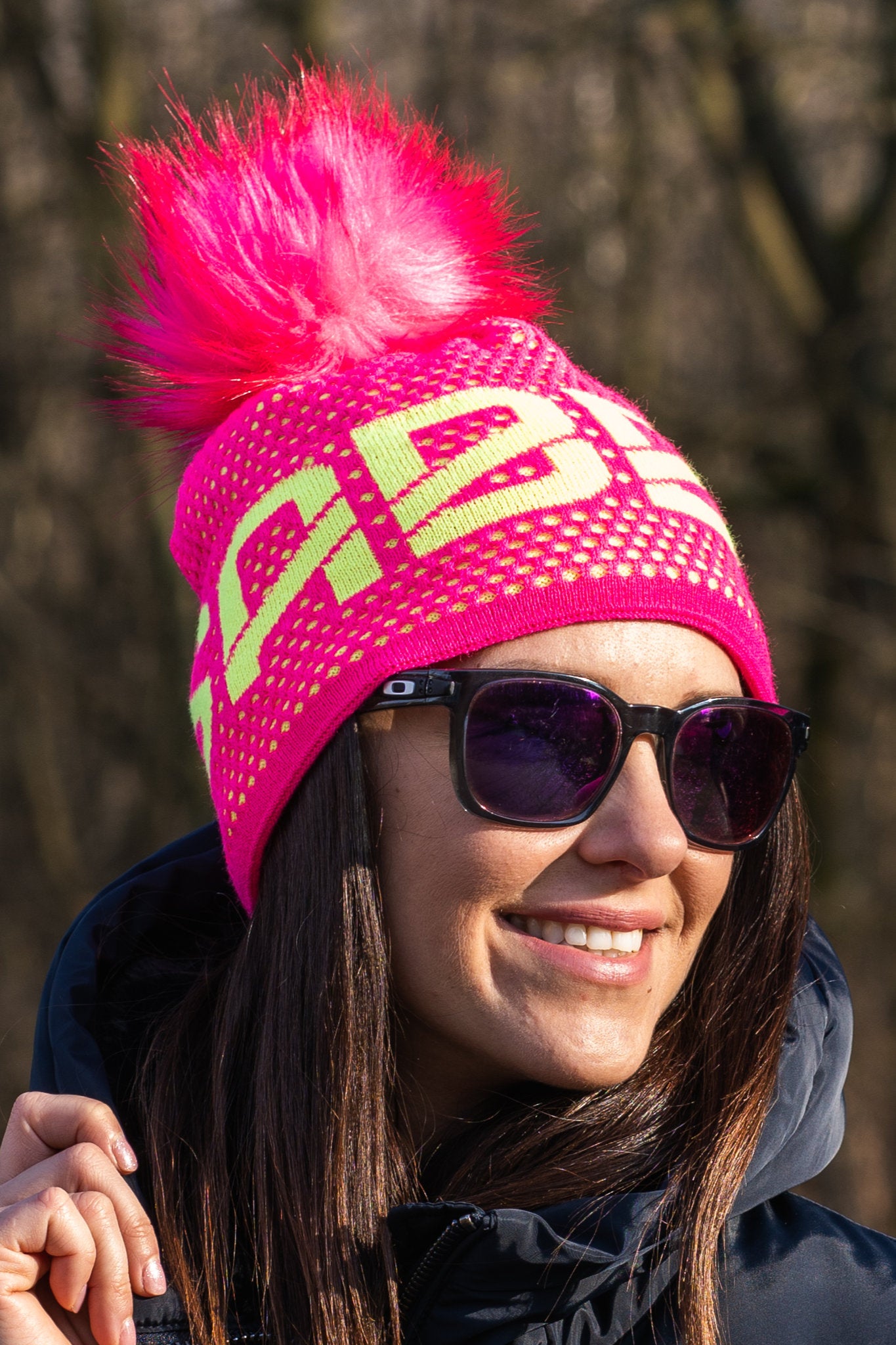 Sabbot Headwear Lady wearing a neon pink SABBOT beanie at a ski resort Sabbot Headwear