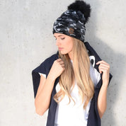 Woman wearing the SABBOT Calli camo bobble hat in black with faux fur pom pom