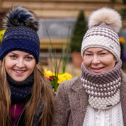 Two women in matching hat and snood sets wearing the Chloe Bobble Hats and Snoods in Navy/Pink and Brown/Cream