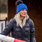 A woman building jumps in a riding arena wearing the Eva Krazi Neon Bobble Hat in Neon Blue