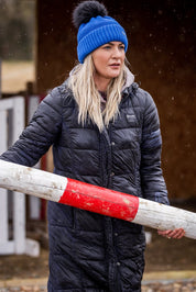 A woman building jumps in a riding arena wearing the Eva Krazi Neon Bobble Hat in Neon Blue