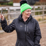 A woman building jumps in a riding arena wearing the Eva Krazi Neon Bobble Hat in Neon Green