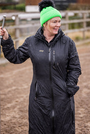 A woman building jumps in a riding arena wearing the Eva Krazi Neon Bobble Hat in Neon Green