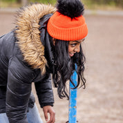 A woman building jumps in a riding arena wearing the Eva Krazi Neon Bobble Hat in Neon Orange