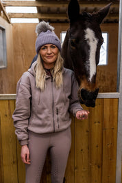 A woman with a horse in the stables wearing the Eva Bobble Hat in Purple