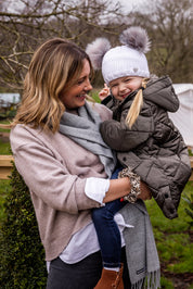 A mum laughing with her toddler outdoors wearing the Frankie Childrens Bobble Hat in White