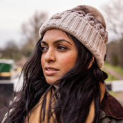 A woman walking a labrador along the canal wearing the Linda Bobble Hat in Cappuccino