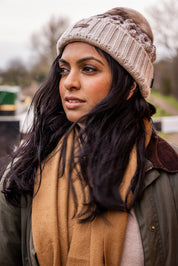A woman walking a labrador along the canal wearing the Linda Bobble Hat in Cappuccino