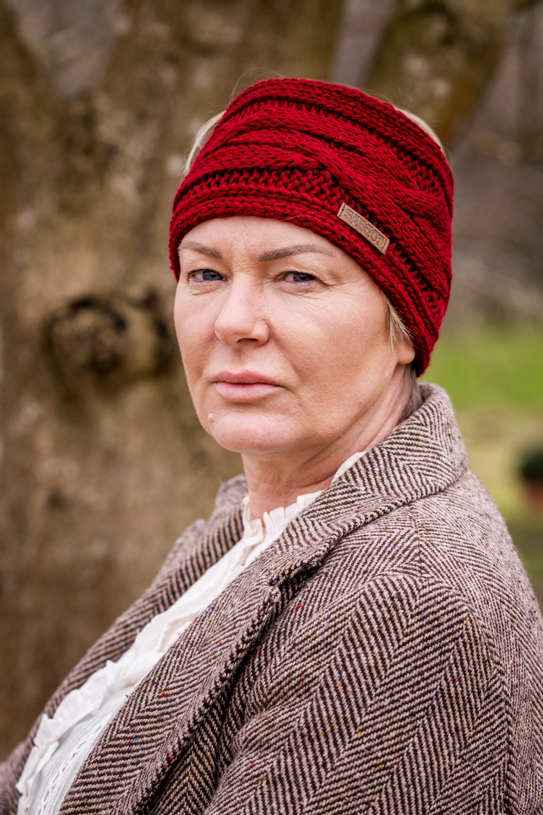 Two women in tweed jackets and riding boots wearing the Linda Headband in Burgundy