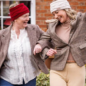 Two women in tweed jackets and riding boots wearing the Linda Headbands in Cream and Burgundy