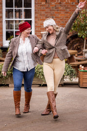 Two women in tweed jackets and riding boots wearing the Linda Headbands in Cream and Burgundy