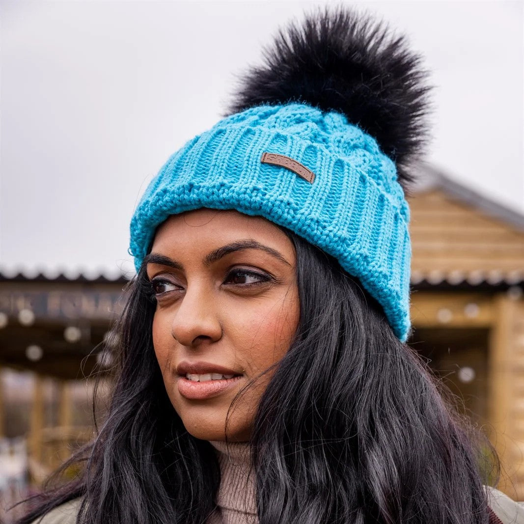 Three friends out walking their dogs wearing the Linda Neon Bobble Hat in Neon Blue