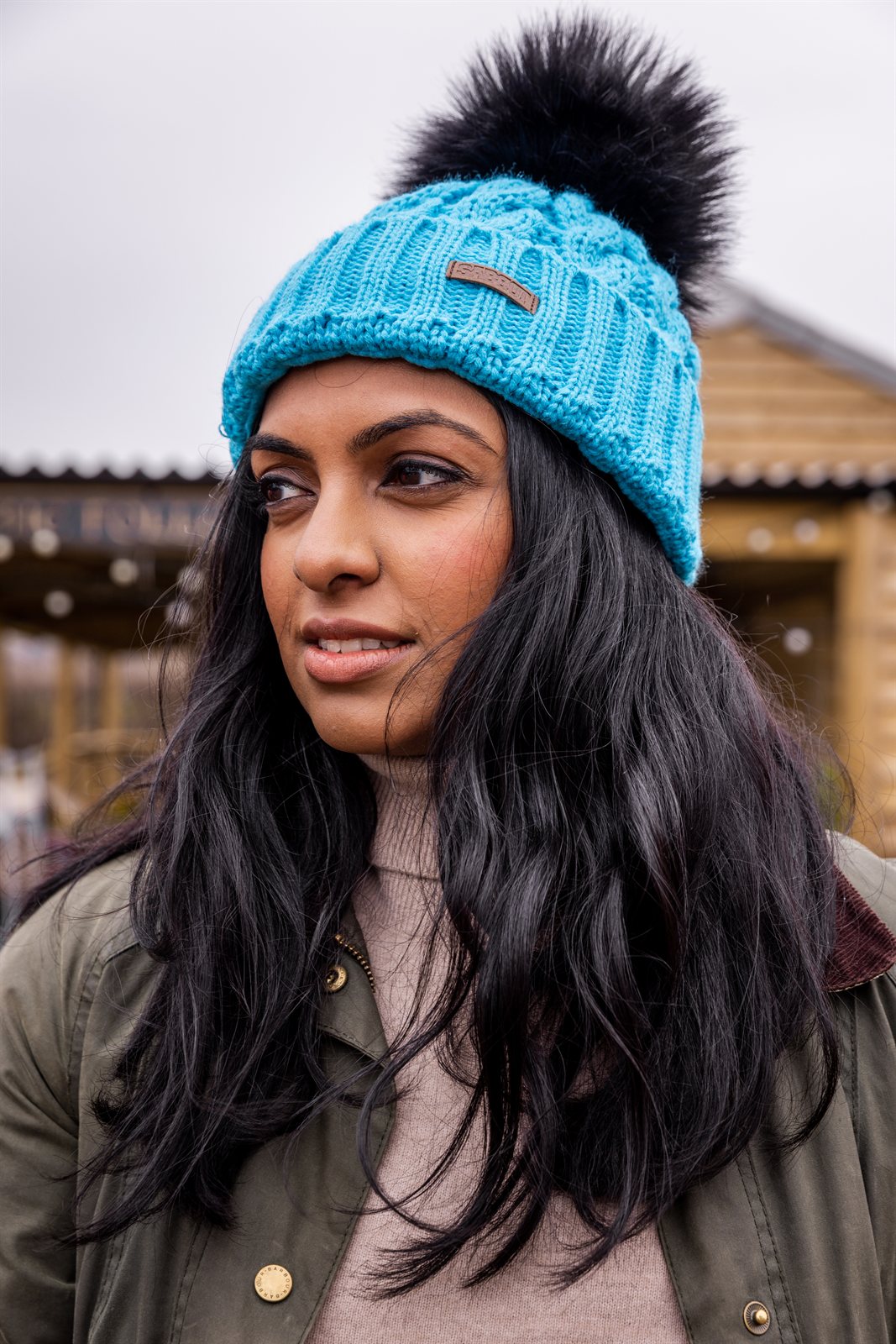 Three friends out walking their dogs wearing the Linda Neon Bobble Hat in Neon Blue