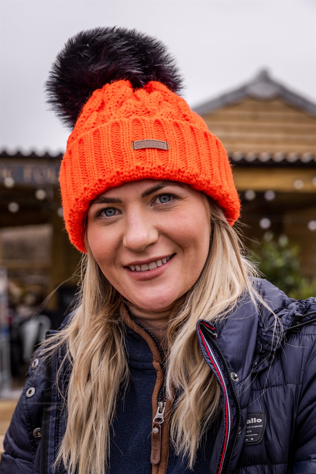 Three friends out walking their dogs wearing the Linda Neon Bobble Hat in Neon Orange