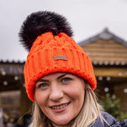 Three friends out walking their dogs wearing the Linda Neon Bobble Hat in Neon Orange