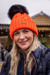 Three friends out walking their dogs wearing the Linda Neon Bobble Hat in Neon Orange