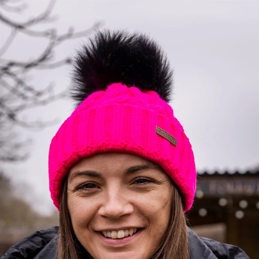 Three friends out walking their dogs wearing the Linda Neon Bobble Hat in Neon Pink