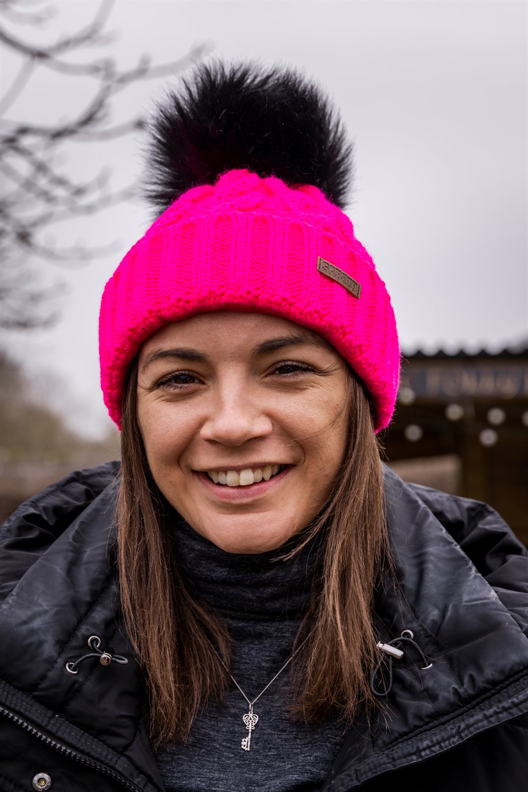 Three friends out walking their dogs wearing the Linda Neon Bobble Hat in Neon Pink