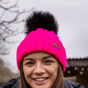 Three friends out walking their dogs wearing the Linda Neon Bobble Hat in Neon Pink