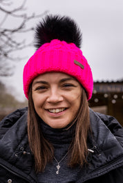 Three friends out walking their dogs wearing the Linda Neon Bobble Hat in Neon Pink