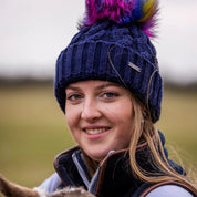 Women cuddling lambs in a field wearing Linda Rainbow Bobble Hat in Navy Blue