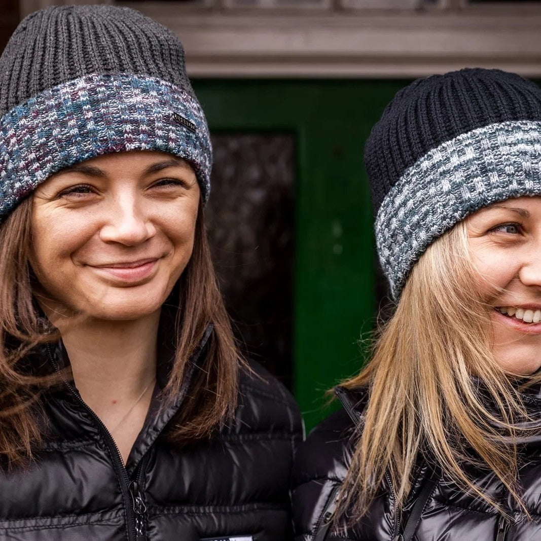 Two women by a red phone box wearing the Morgan Beanies in Black Camo and Grey Camo