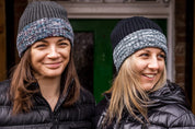 Two women by a red phone box wearing the Morgan Beanies in Black Camo and Grey Camo