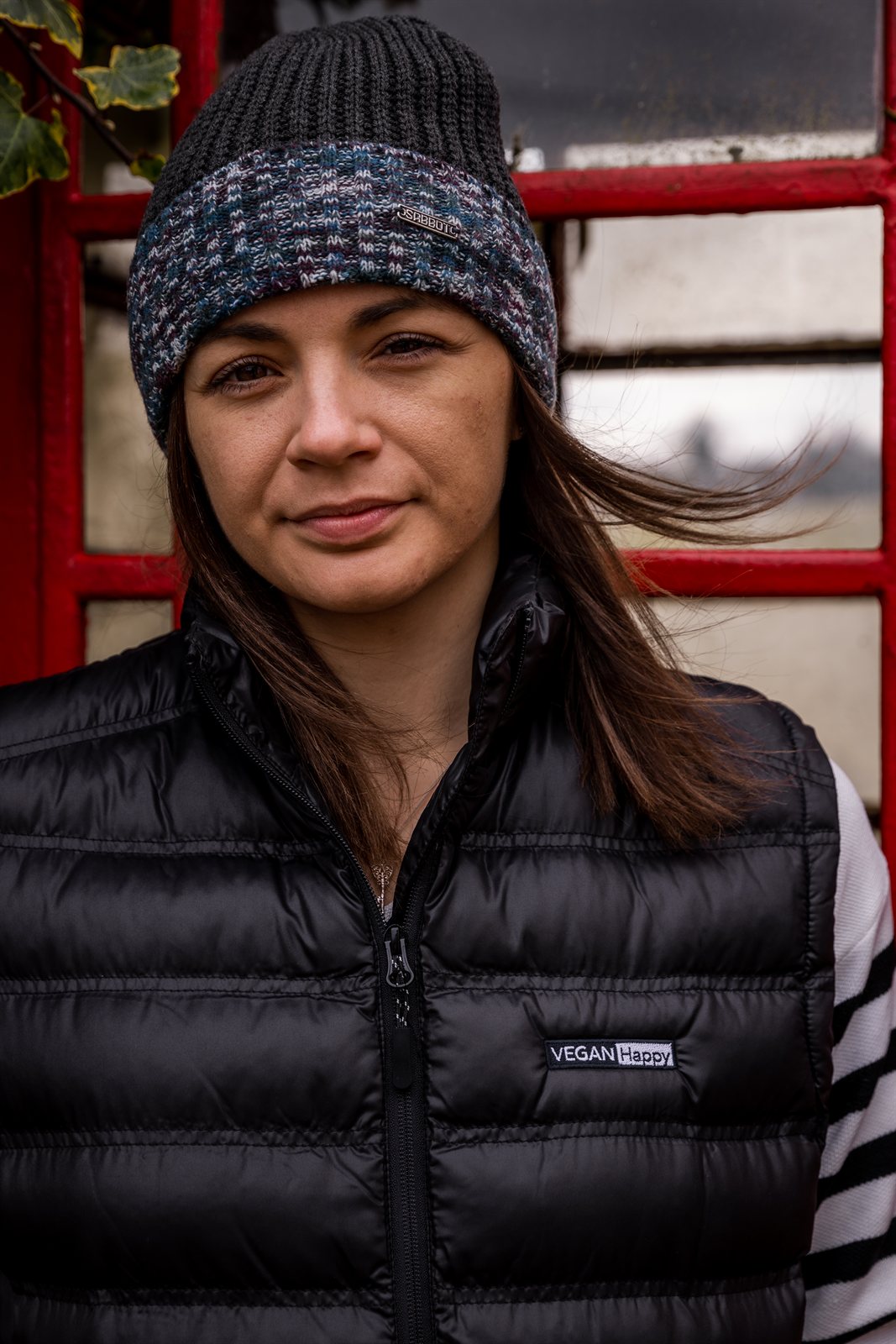 Two women by a red phone box wearing the Morgan Beanie in Black Camo