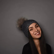 A woman in a black top wearing the SABBOT Radka Bobble Hat