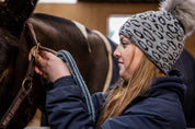 Friends with mugs in a tack room and stables wearing the Saskia Bobble Hat in Grey/Black