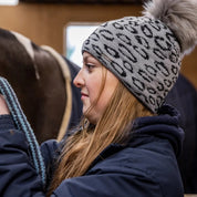 Friends with mugs in a tack room and stables wearing the Saskia Bobble Hat in Grey/Black