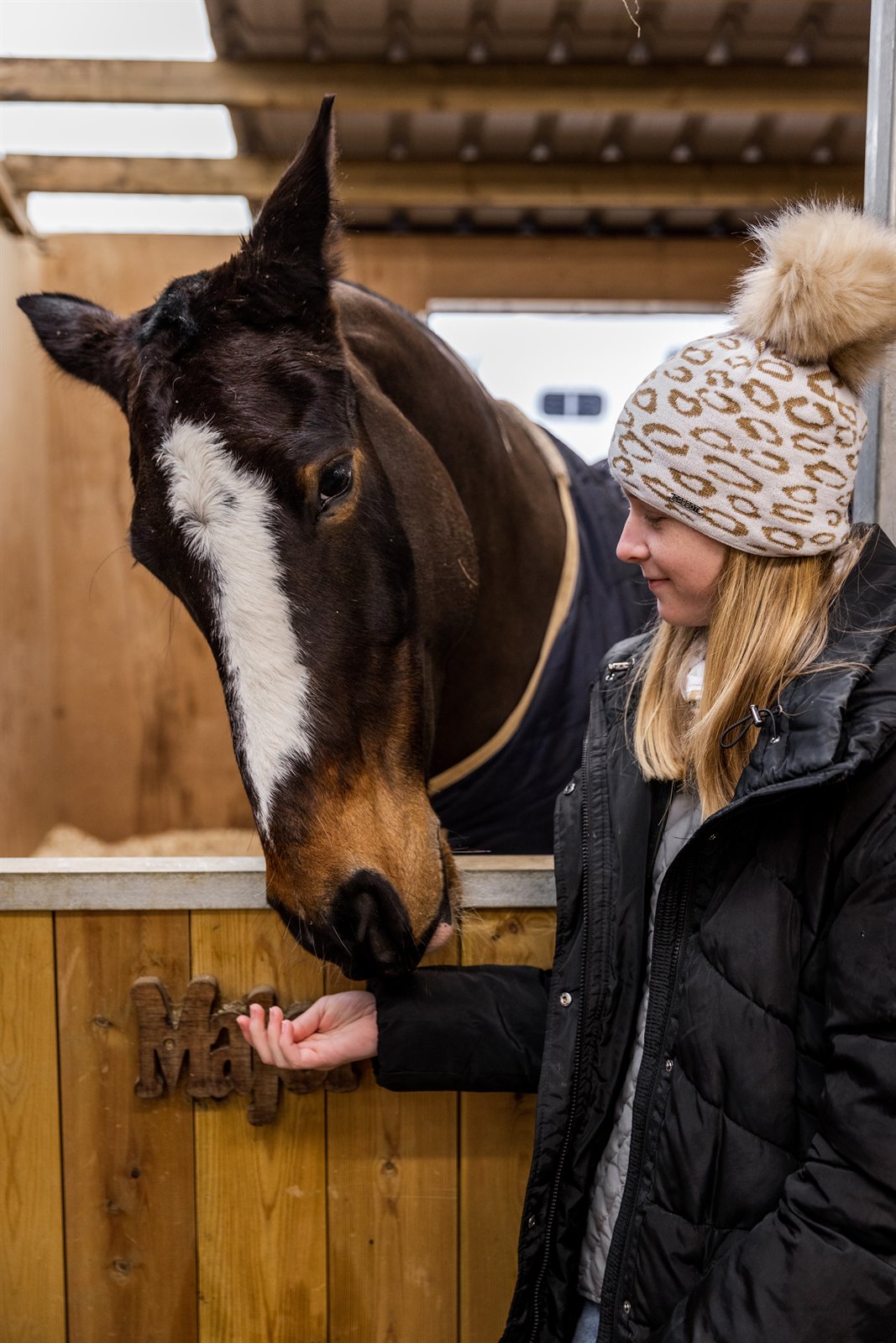 Friends with mugs in a tack room and stables wearing the Saskia Bobble Hat in White/Gold