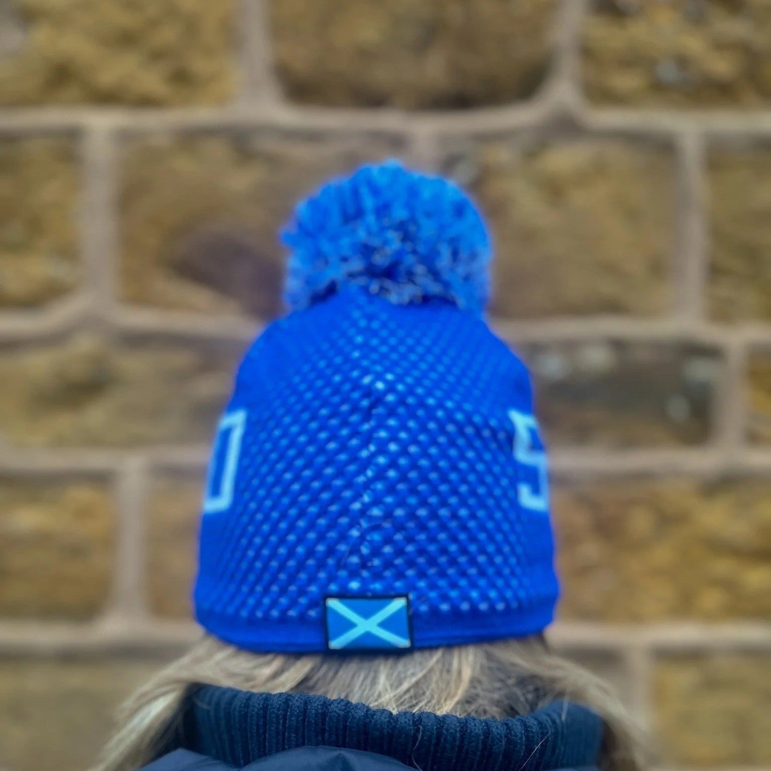 Back view of the SABBOT Scotland Bobble Hat showing the pom pom and saltire flag tab