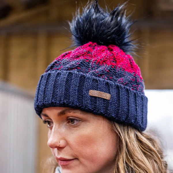 A woman in a navy and red chunky two-tone knit wearing the SABBOT Zuzana Bobble Hat